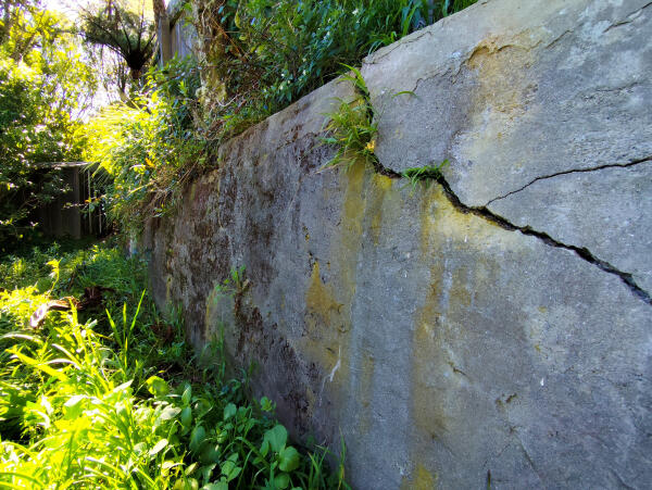 A concrete retaining wall with a large crack through the middle.