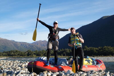 Sophie and a man standing on a riverbed infront of inflatable boats.