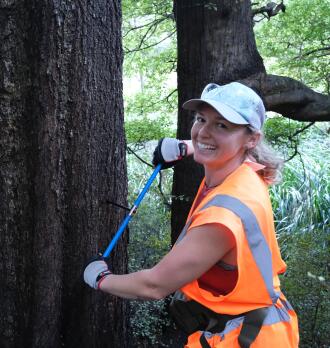 Sophie standing in front of a tree with a measuring device.