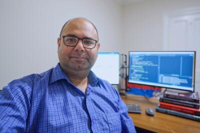 Man sitting at his desk in front of his computer screens.