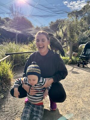 A woman holds a toddler smiling at the camera.