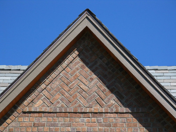 The roof of a house, showing a pointed brick roof at the front of the house.bone brick 