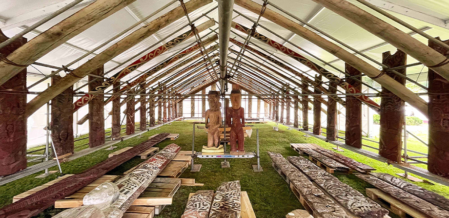 A pop-up marae with carvings lying on the ground.