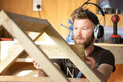A man building something with timber in a workshop.