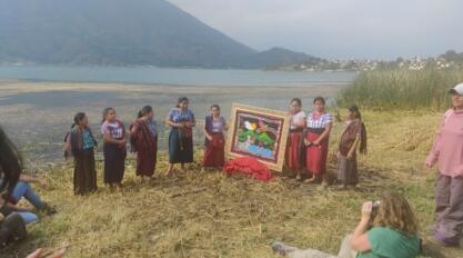 A group of Māori women standing on a riverbed holding a painting.