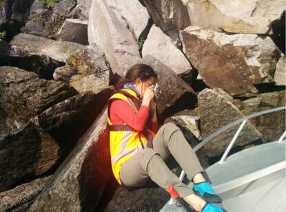 Kate sitting on a rock taking a photograph.
