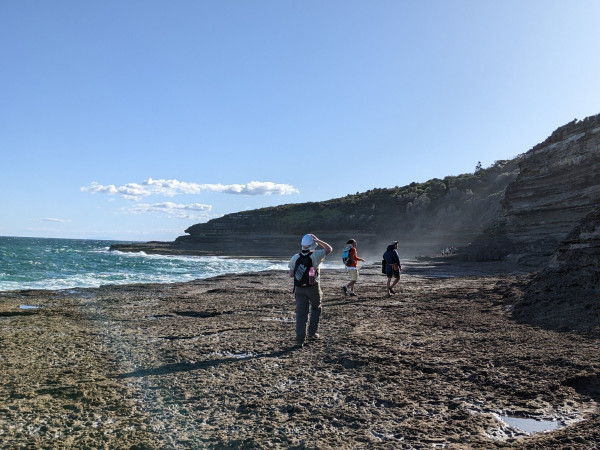 Three researchers walk next to the sea