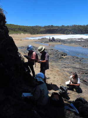 Researchers standing on rock formations next to the sea