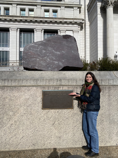 Meegan smiling in front of a plaque at a museum.
