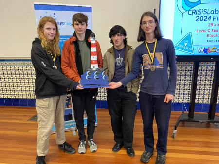 Four students hold up their model