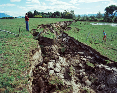 Man looks into big land rupture across a field