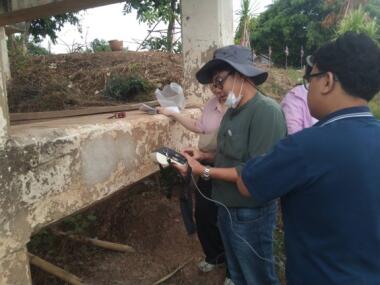 Four people look at a piece of concrete on a demolition site.