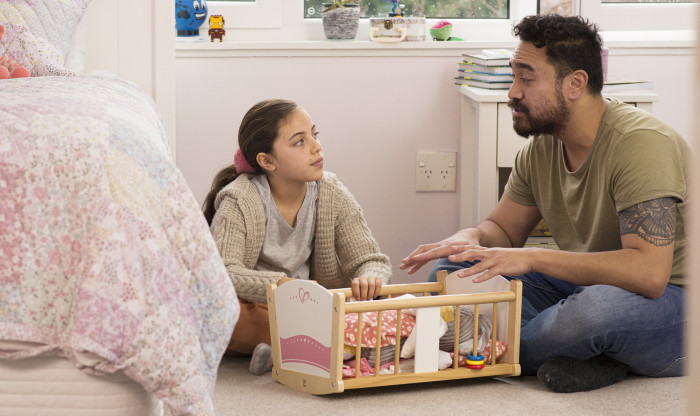Father and daughter sitting on the floor in a child's bedroom