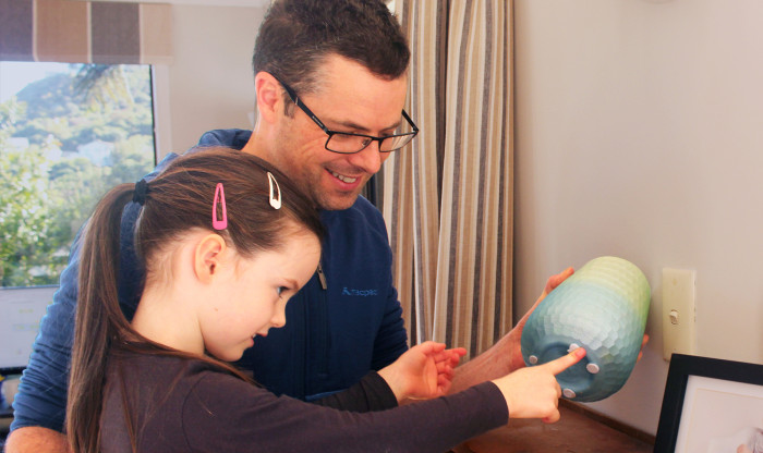A man and child secure a vase to the drawers with blu tac