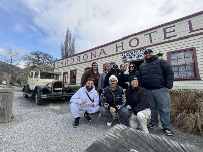 A group of people smiling together in front of a tavern called 'Cardrona Hotel.'